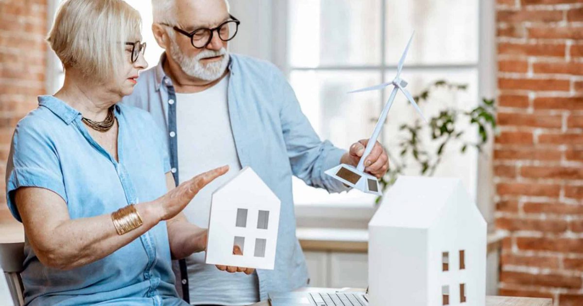 Senior Couple Holding a house and wind turbine model.